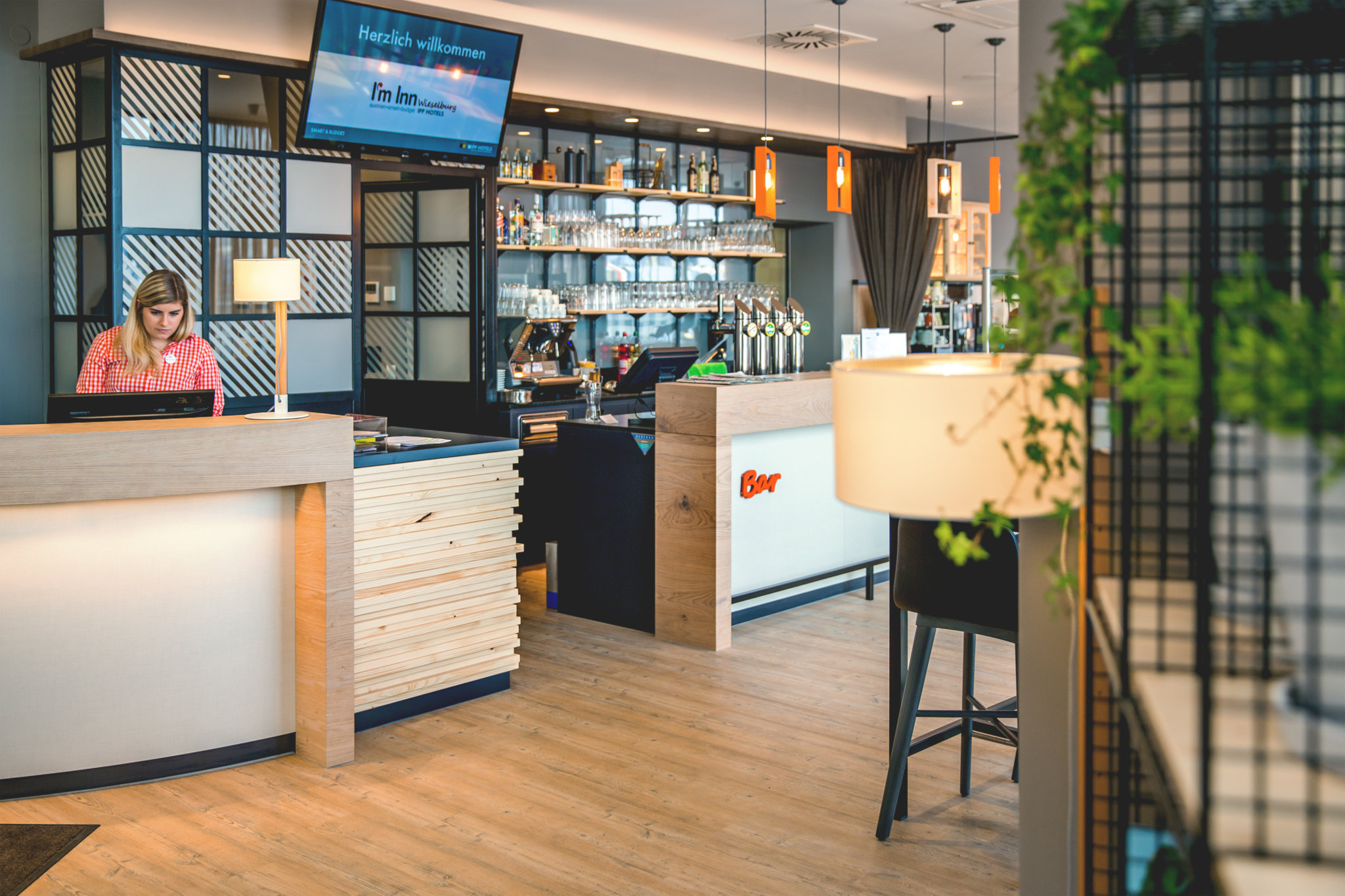 Moderner, freundlicher Empfangsbereich des I'm Inn Wieselburg mit Rezeption und Bar